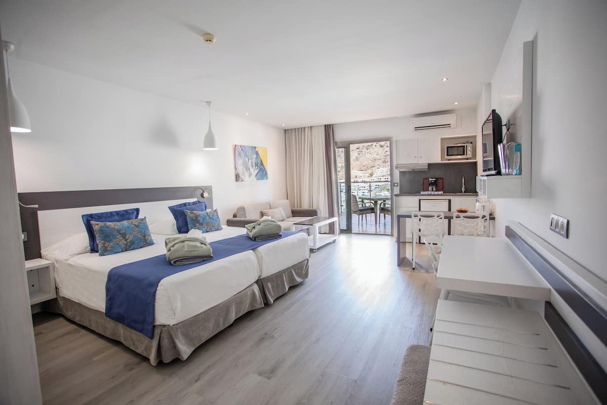 Ein modernes Hotelzimmer mit einem großen Bett, einem Schreibtisch und einer Küchenzeile.