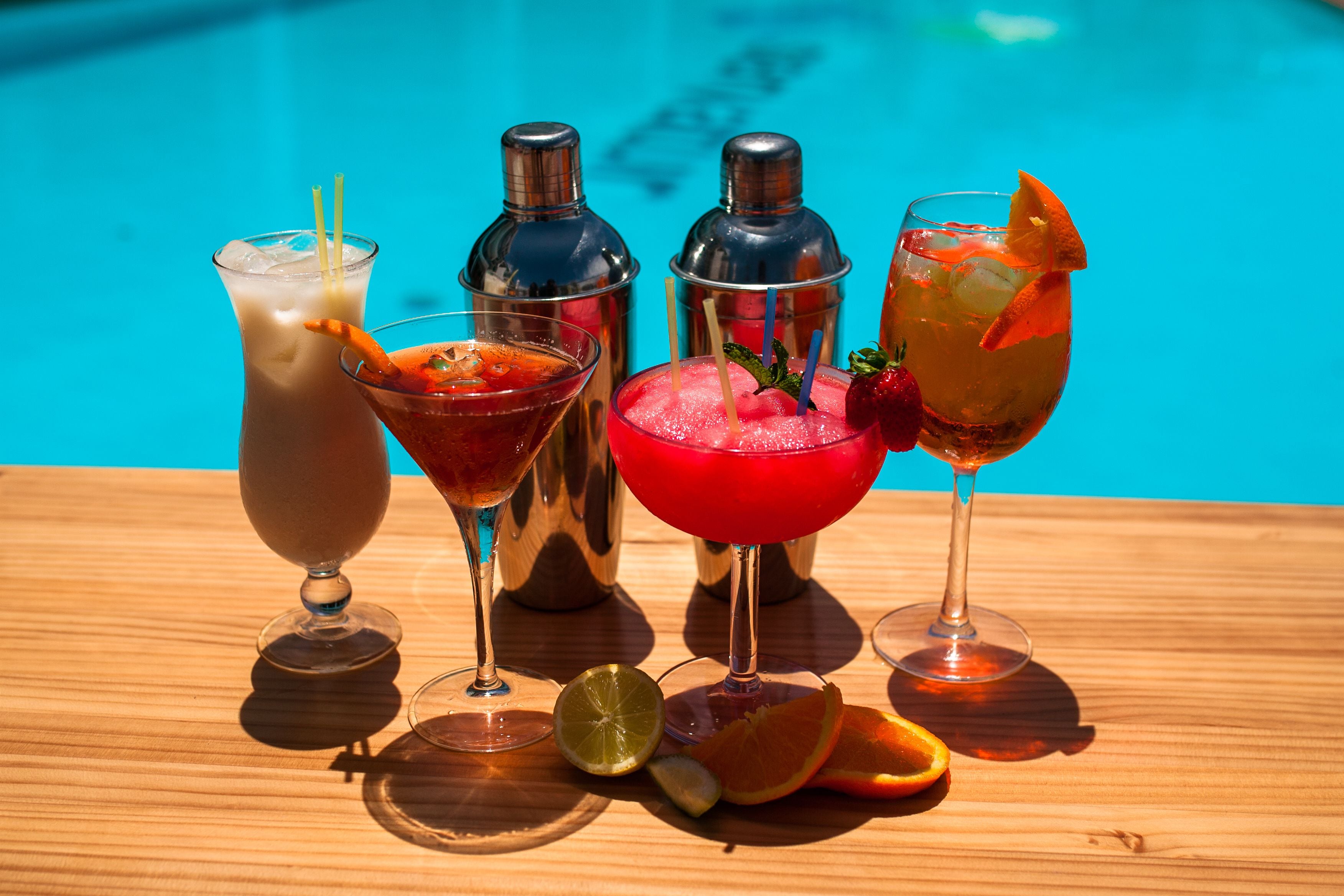 A wooden table with various drinks and cocktail shakers.