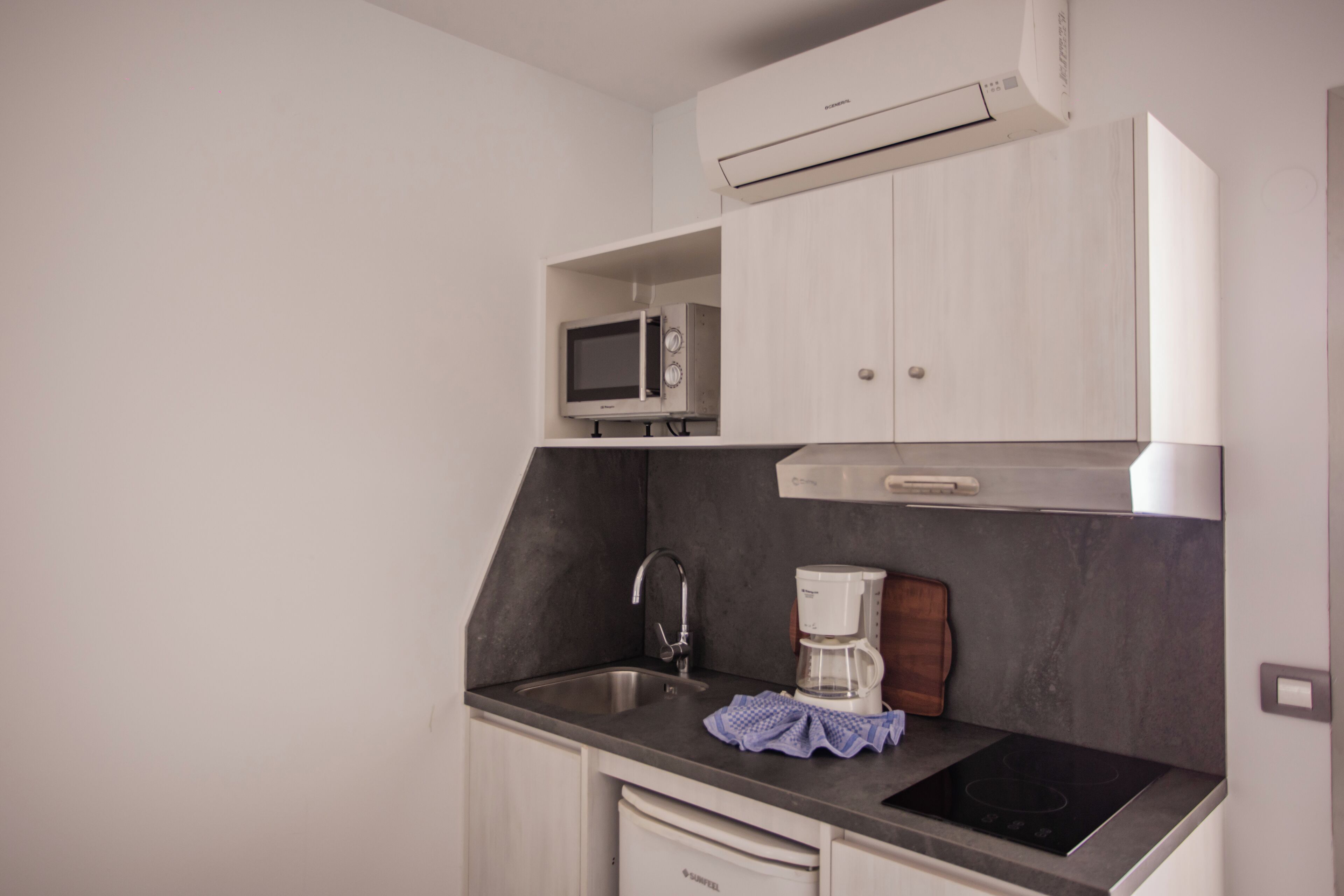 A compact kitchen with a microwave, coffee maker, and a built-in oven.