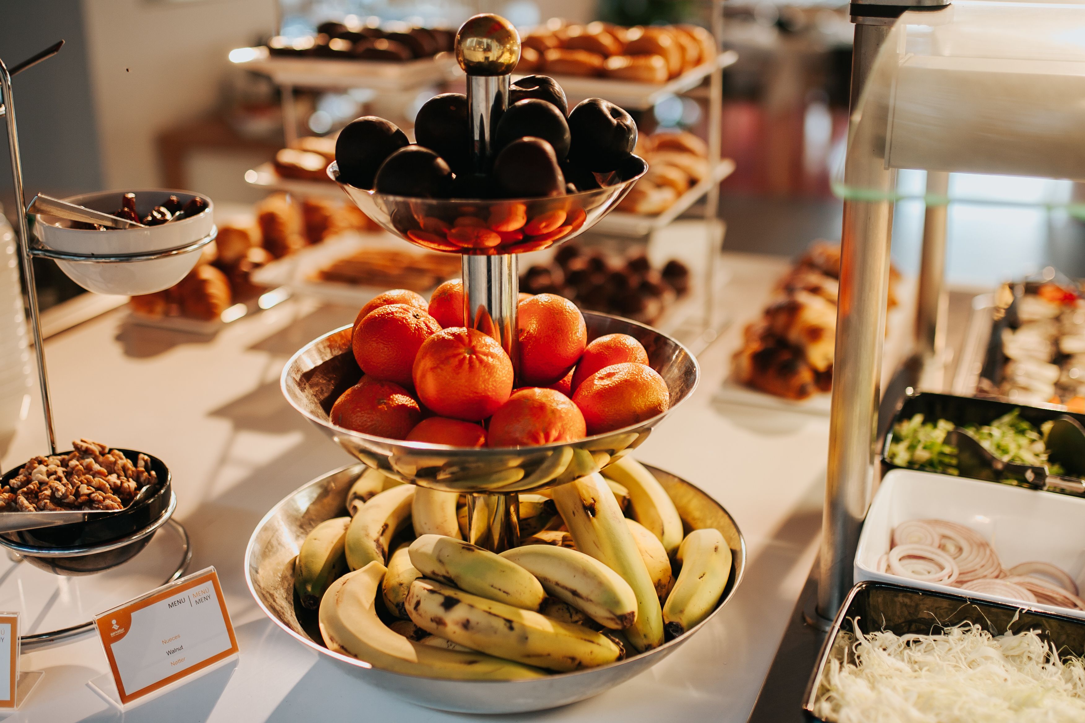 Un bufé con diversos alimentos, como plátanos, naranjas y pasteles.