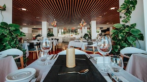Ein Restaurant mit Holzbalkendecke, gedeckten Tischen, Weingläsern, Tellern und Besteck.