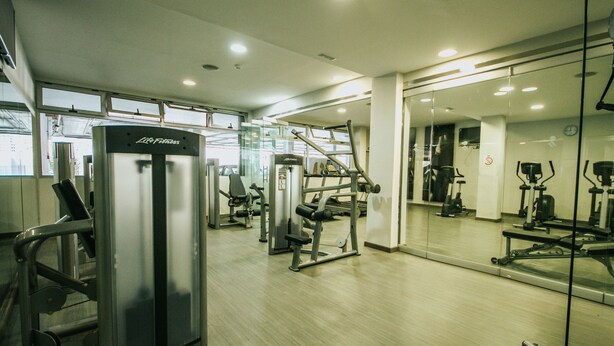 A gym with various exercise machines, a large mirror, and a wooden floor. - Servatur Casablanca Suites & Spa - Adults Only (Mogan)