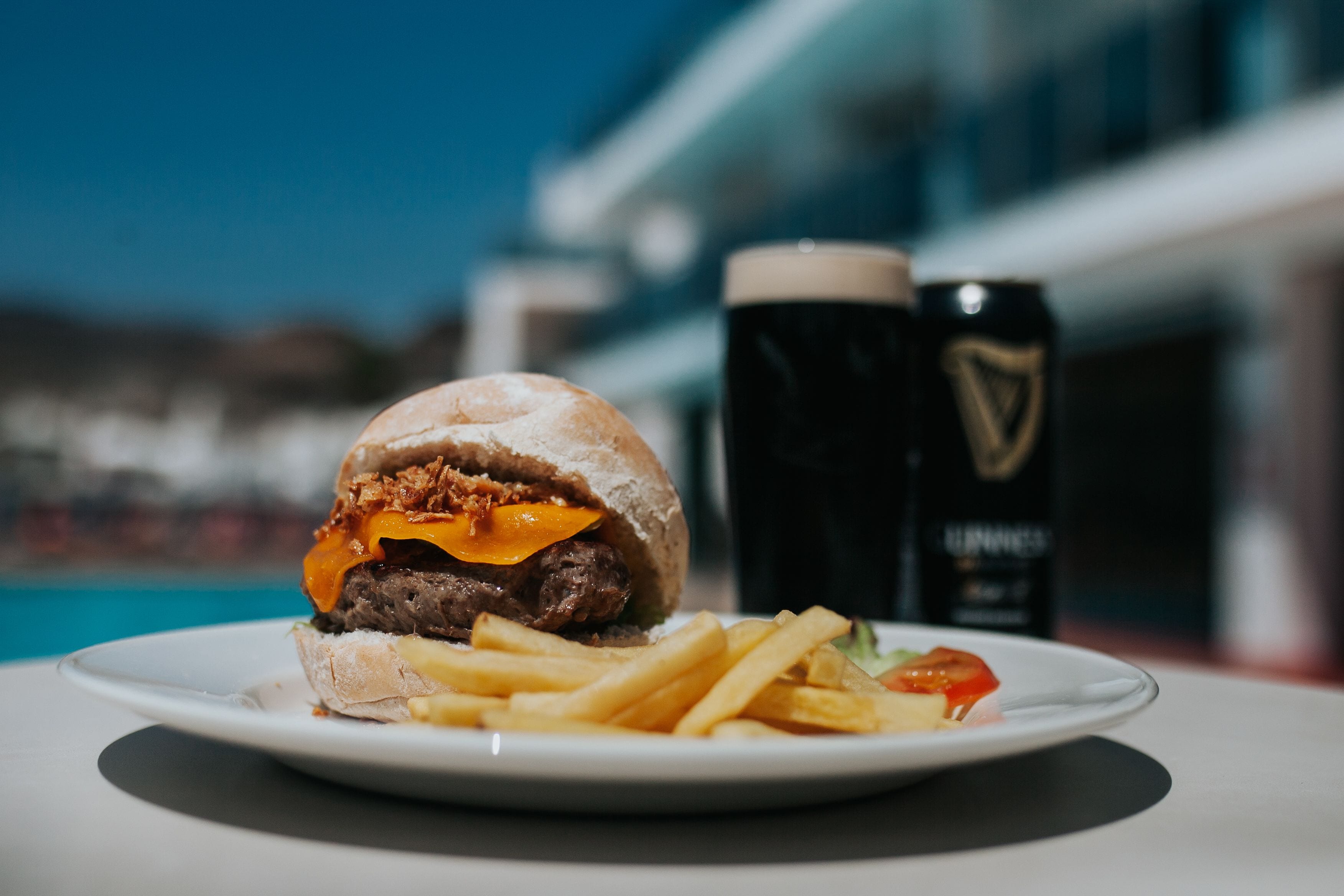 A meal consisting of a burger and fries on a plate, with a beer mug in the background.