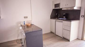 A compact kitchen with a dark countertop, white cabinets, a microwave, and a coffee maker.