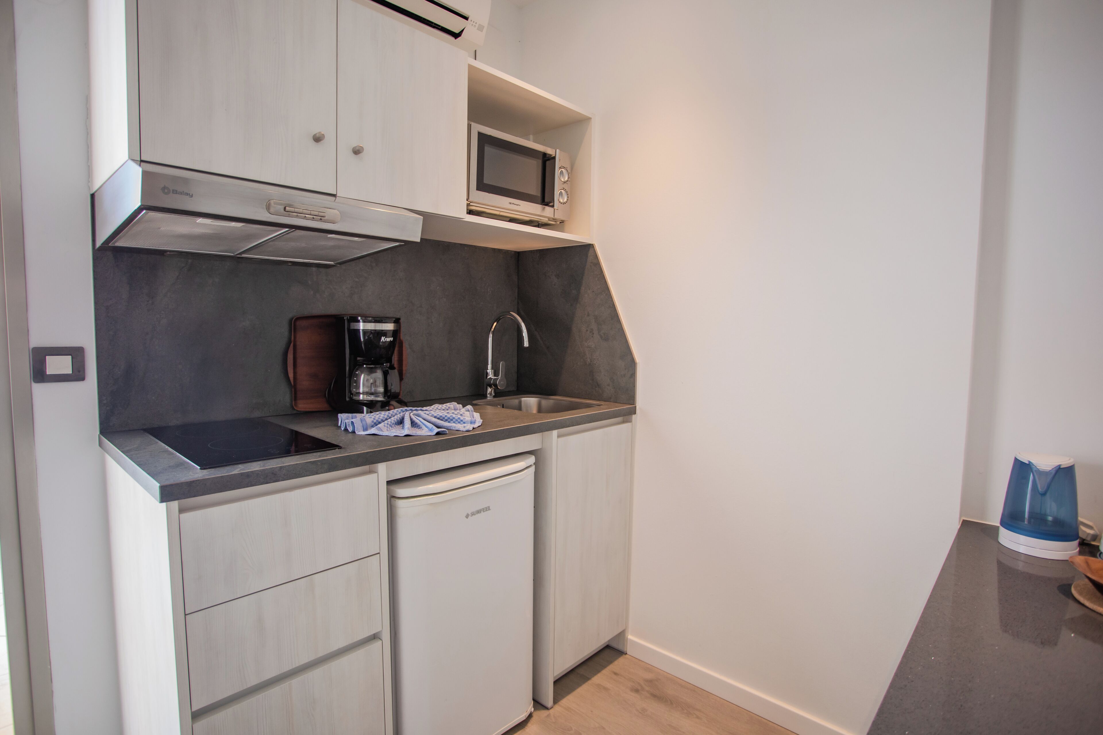 Una cocina compacta con microondas integrado, cafetera y lavavajillas.