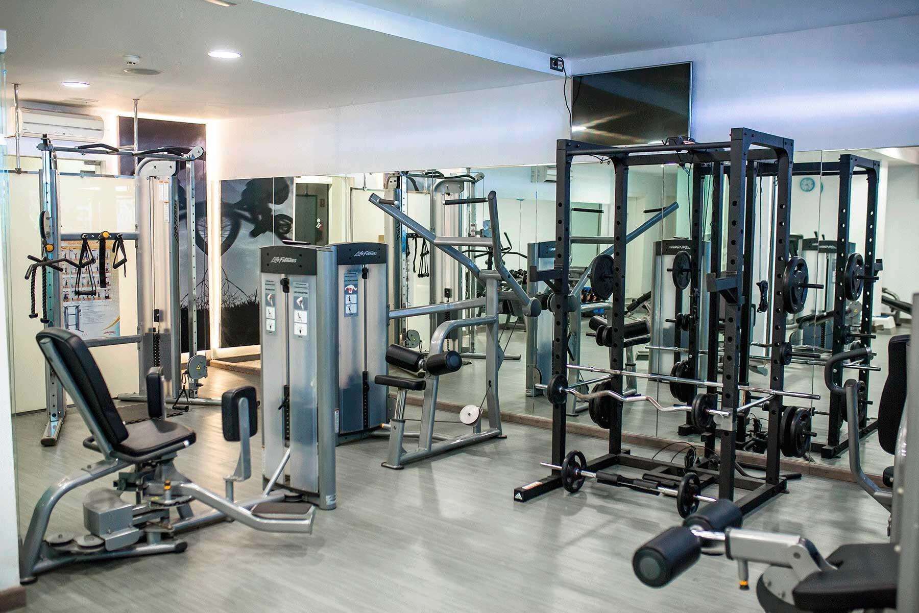 Ett gym med olika träningsmaskiner, speglar och utrustning för styrketräning.