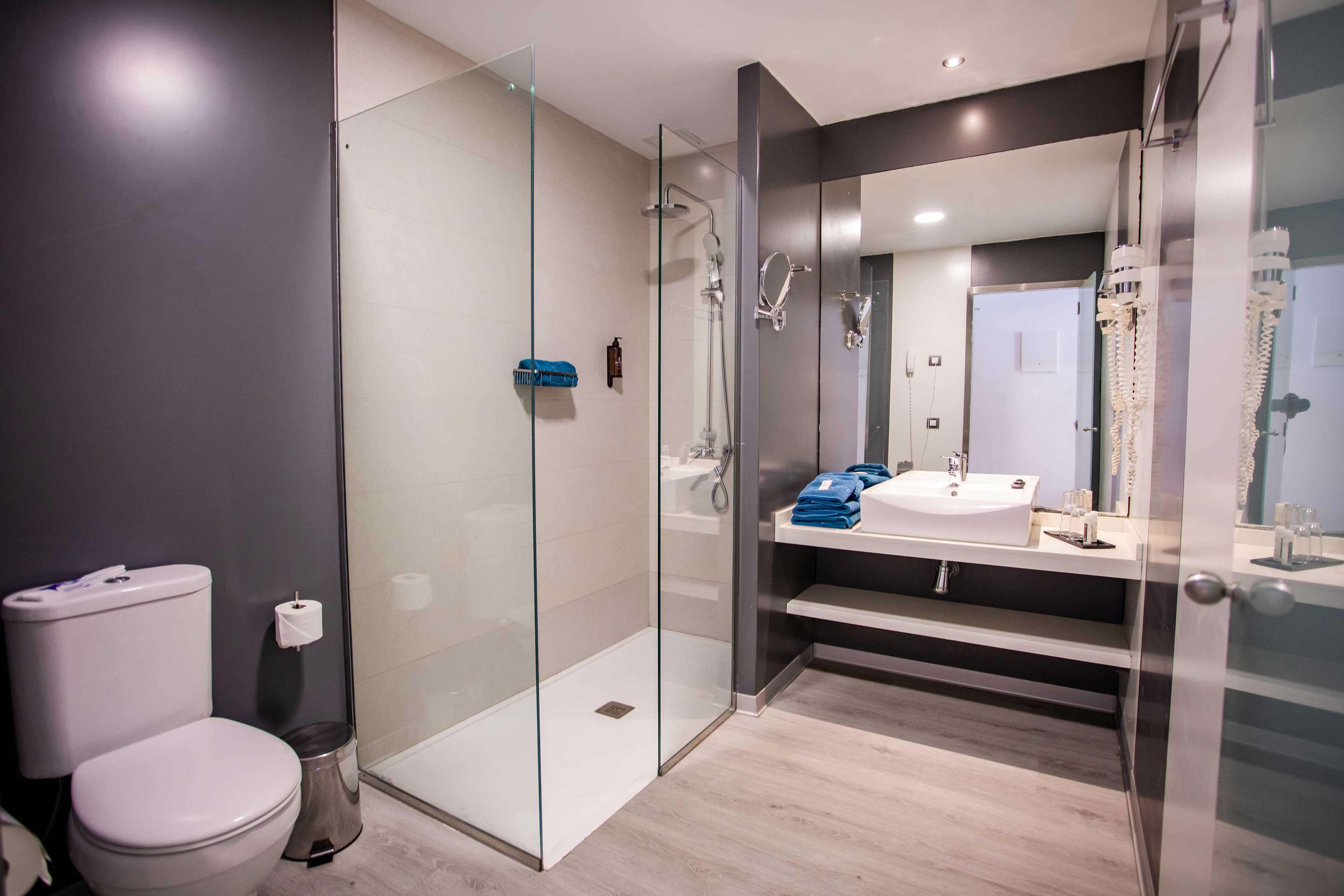 Un baño moderno con ducha envuelta en vidrio, inodoro blanco y tocador con espejo.