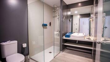 Un baño moderno con ducha envuelta en vidrio, inodoro blanco y tocador con espejo.
