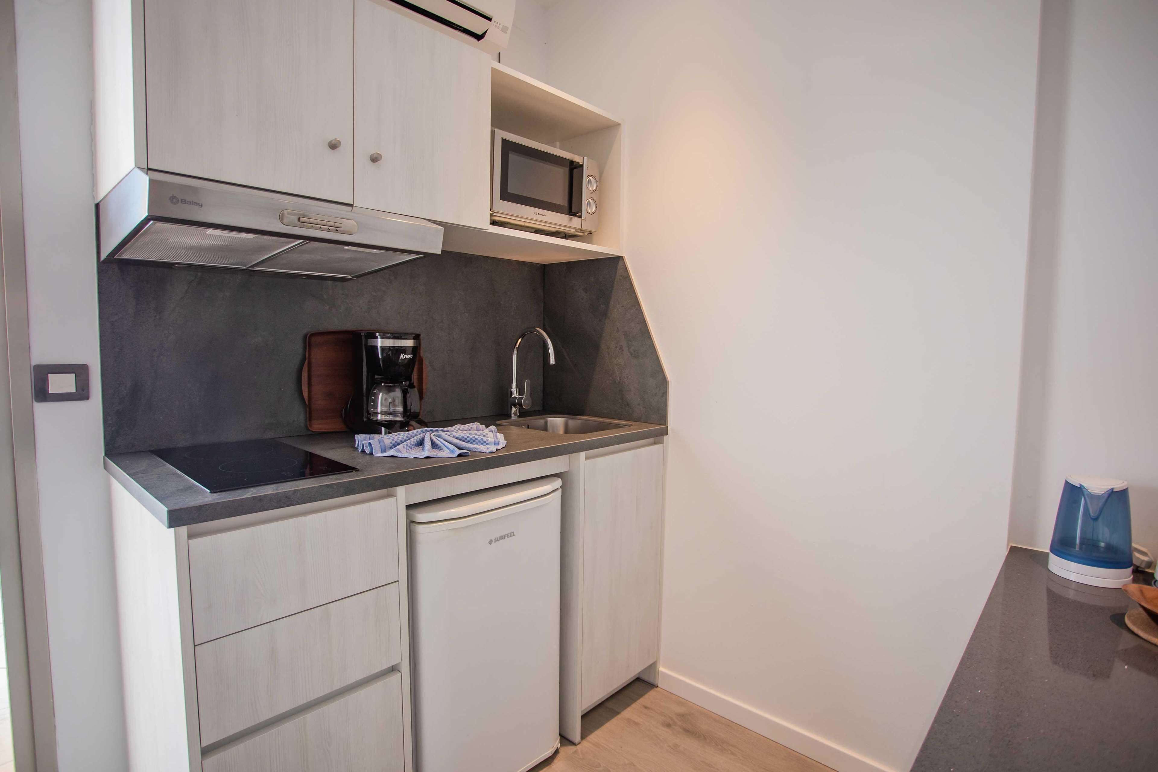 A compact kitchen with a built-in microwave, a coffee maker, and a dishwasher.