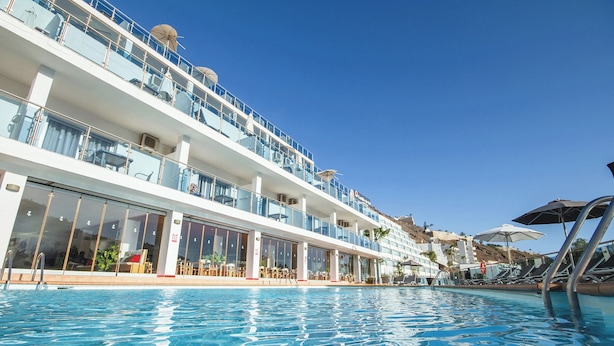 Ein Kreuzfahrtschiff mit Pool, mehreren Decks und Außenbereichen mit Sitzgelegenheiten.