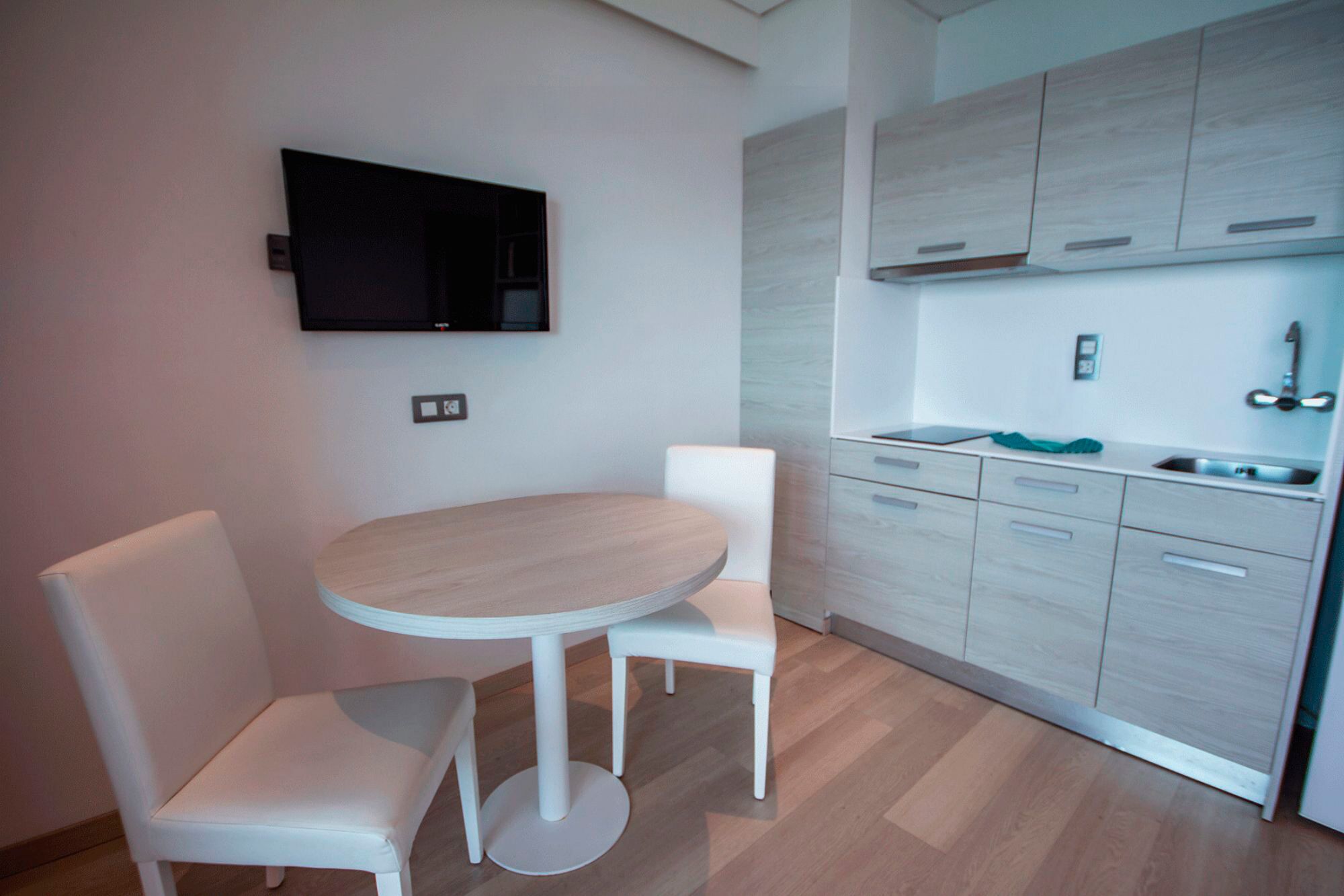 Une cuisine moderne avec des meubles blancs, une table ronde et deux chaises.