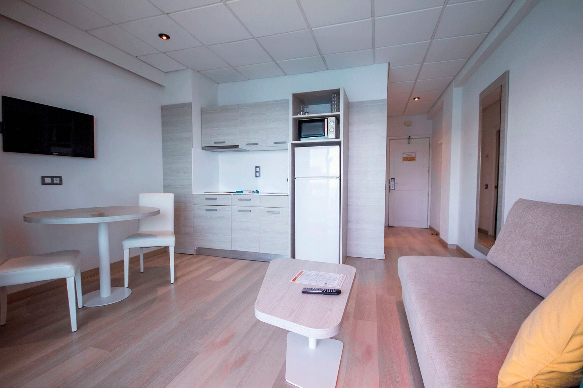 Una sala de estar moderna con un sofá, una mesita y un televisor montado en la pared.