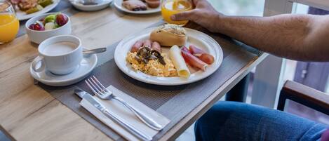 Une table de petit-déjeuner avec des assiettes remplies de nourriture, une tasse de café et un verre de jus d’orange.