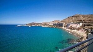 A coastal hotel with multiple buildings along the beachfront, clear blue waters, and a mountainous backdrop. - Servatur Green Beach (Mogan)