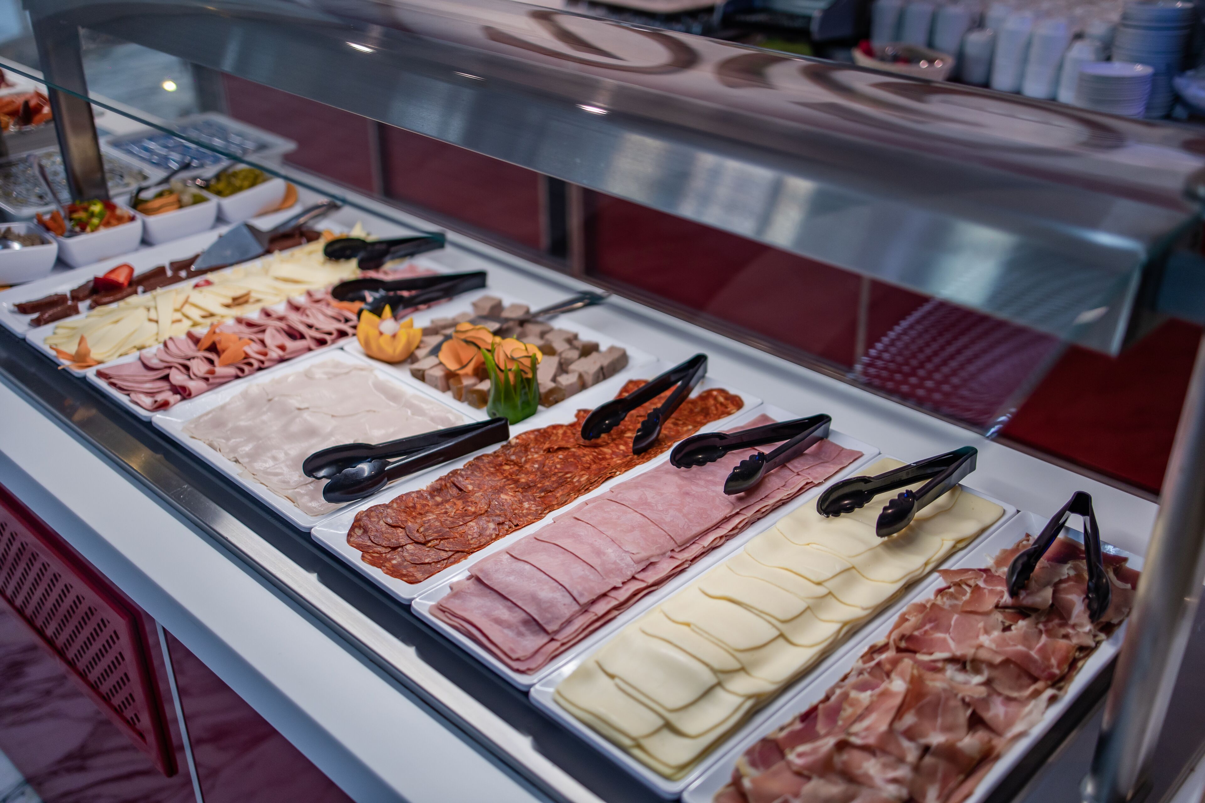Un bufé con diversas opciones de comida, incluyendo carnes, quesos y postres.