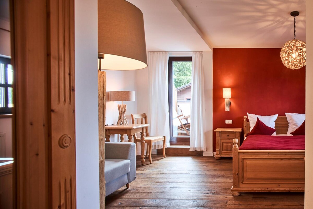 Une chambre avec un lit, un bureau, une chaise, une lampe et une vue sur l’extérieur.