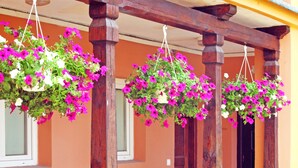 Varanda com guarda-corpo de madeira e cestos suspensos com flores.