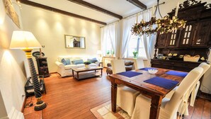 Uma sala de estar acolhedora com uma mesa de jantar de madeira, sofá branco e um armário de madeira escura.
