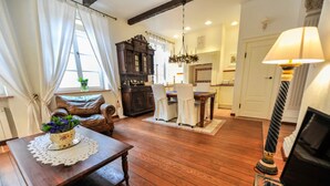 Uma sala de estar aconchegante com uma mesa de centro de madeira, um sofá e um espaço de jantar com um candelabro.