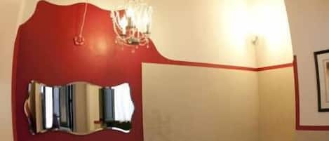 A bathroom with a red accent wall, a chandelier, a freestanding bathtub, and a sink with a towel rack.