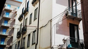 A multi-story building with balconies, a visible ENEL electricity box, and a parked car in front. - Casalicchio B&B (Trapani)