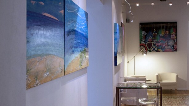 An art gallery with a wooden floor, white walls, and ceiling beams. - Casalicchio B&B (Trapani)