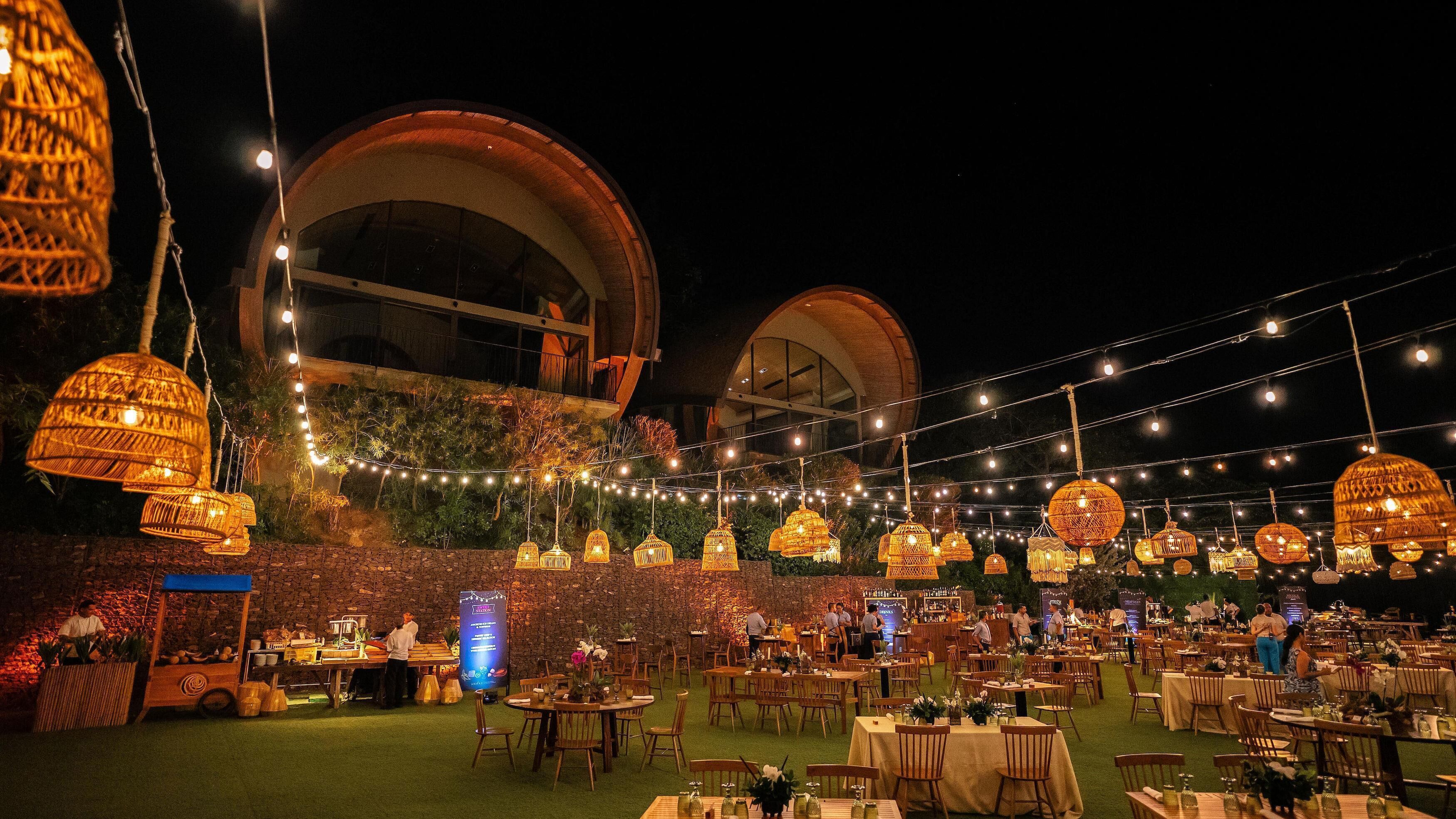 An outdoor dining area with tables and chairs, string lights, and decorative hanging lights.