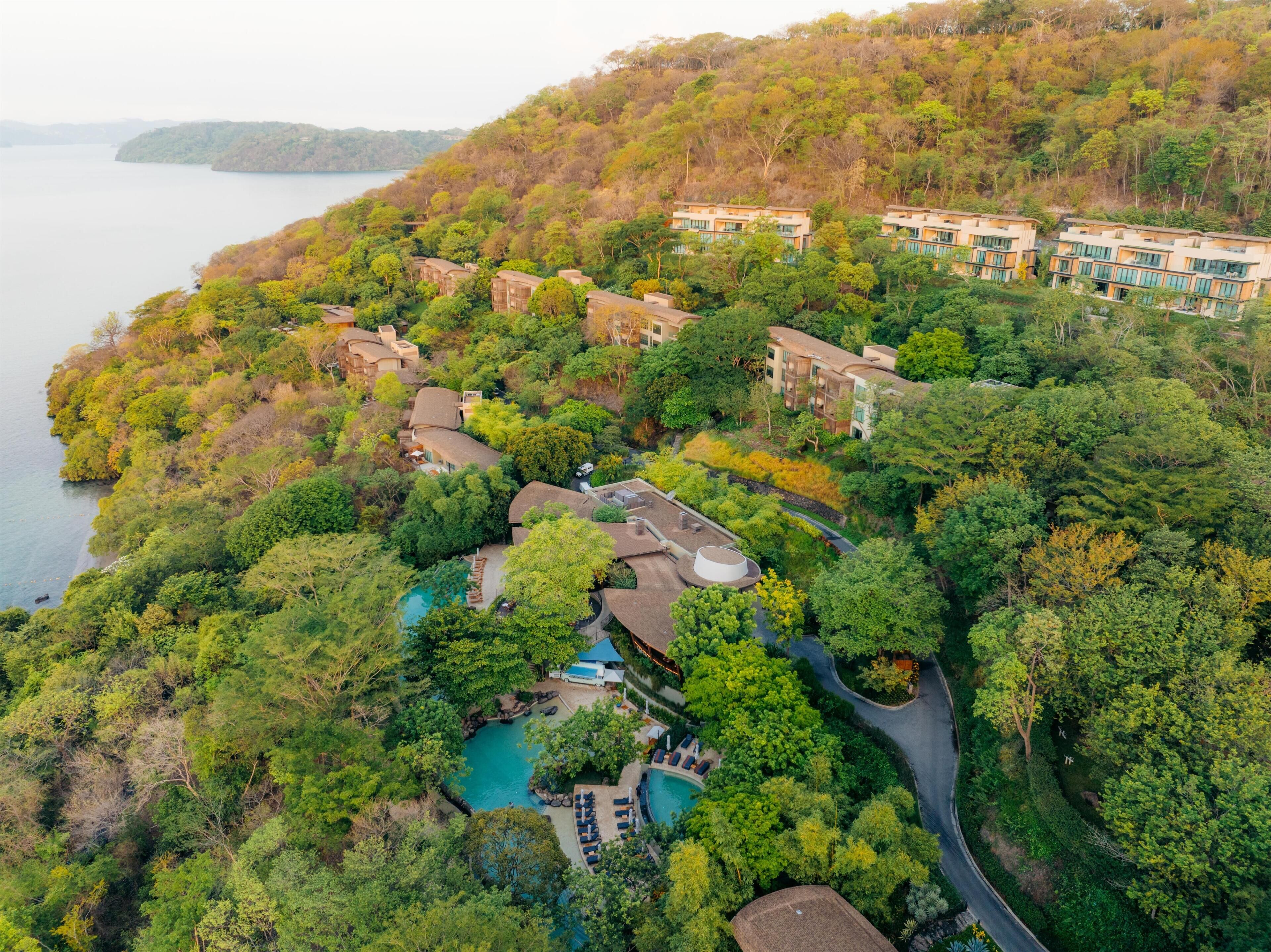 An aerial view of a resort with multiple buildings, a swimming pool, and a road.