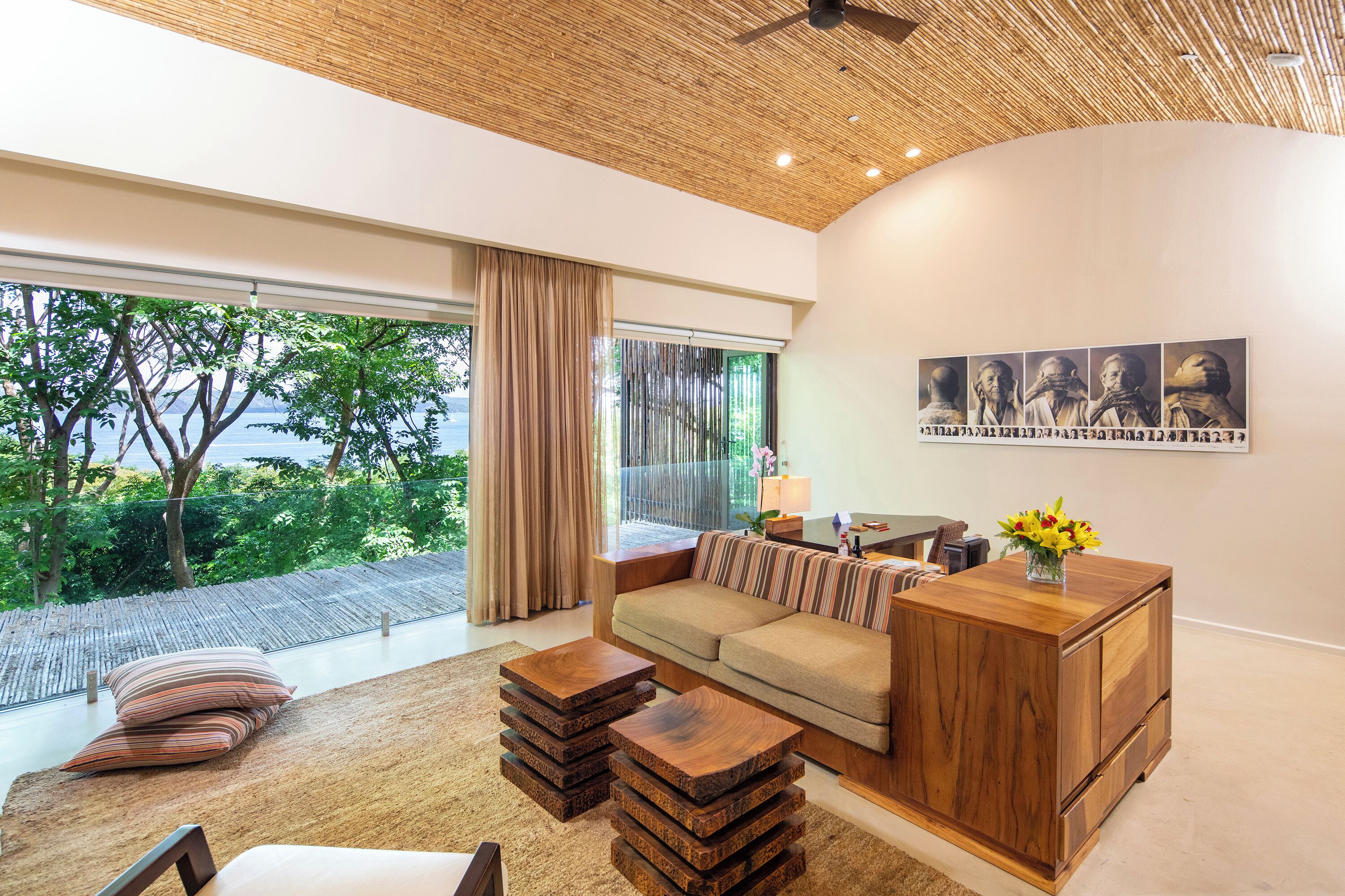 A modern living room with a large window, a sofa, a wooden coffee table, and a wooden cabinet.