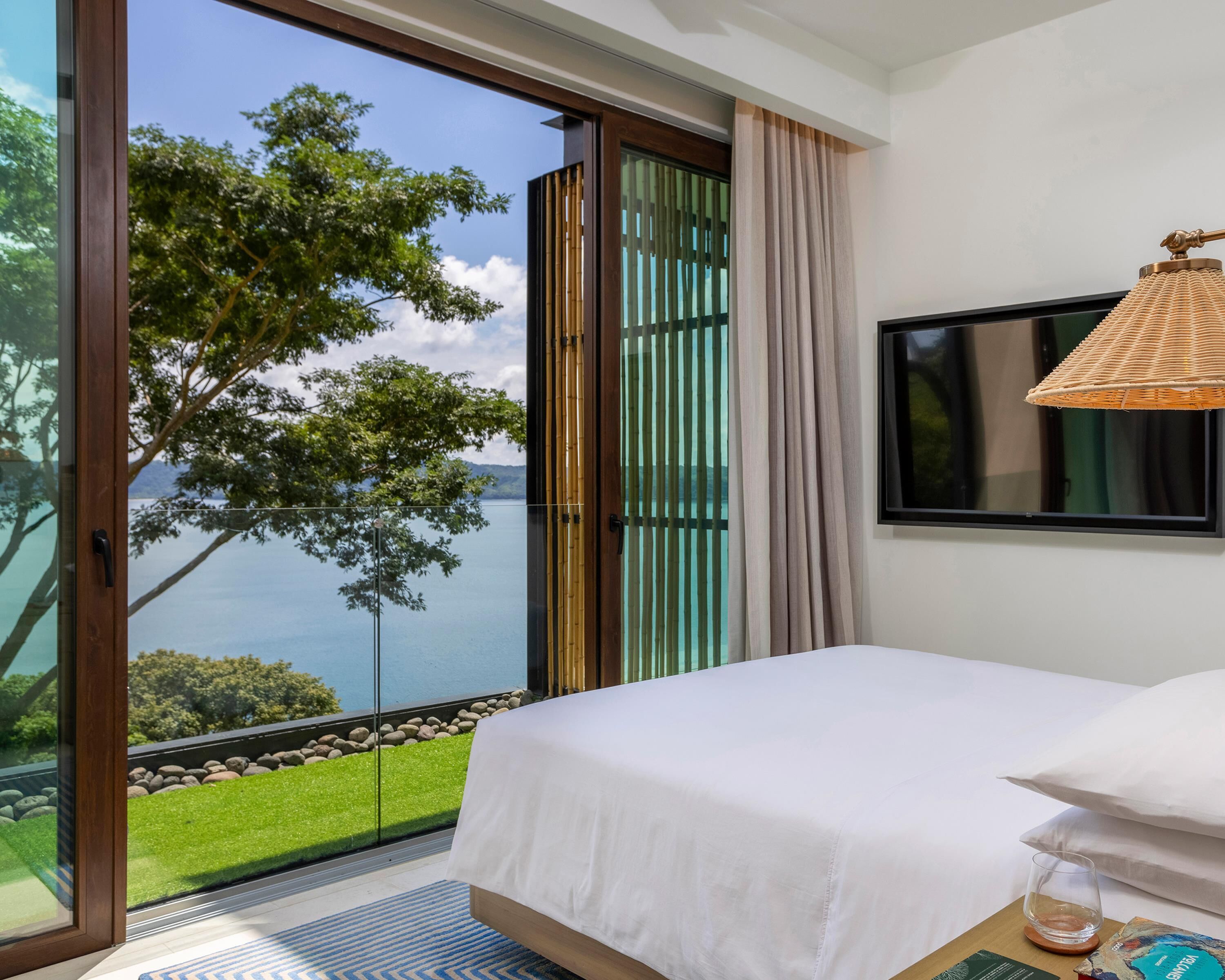 A bedroom with a bed, a television, and a view of a lake.