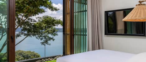 A bedroom with a bed, a television, and a view of a lake.