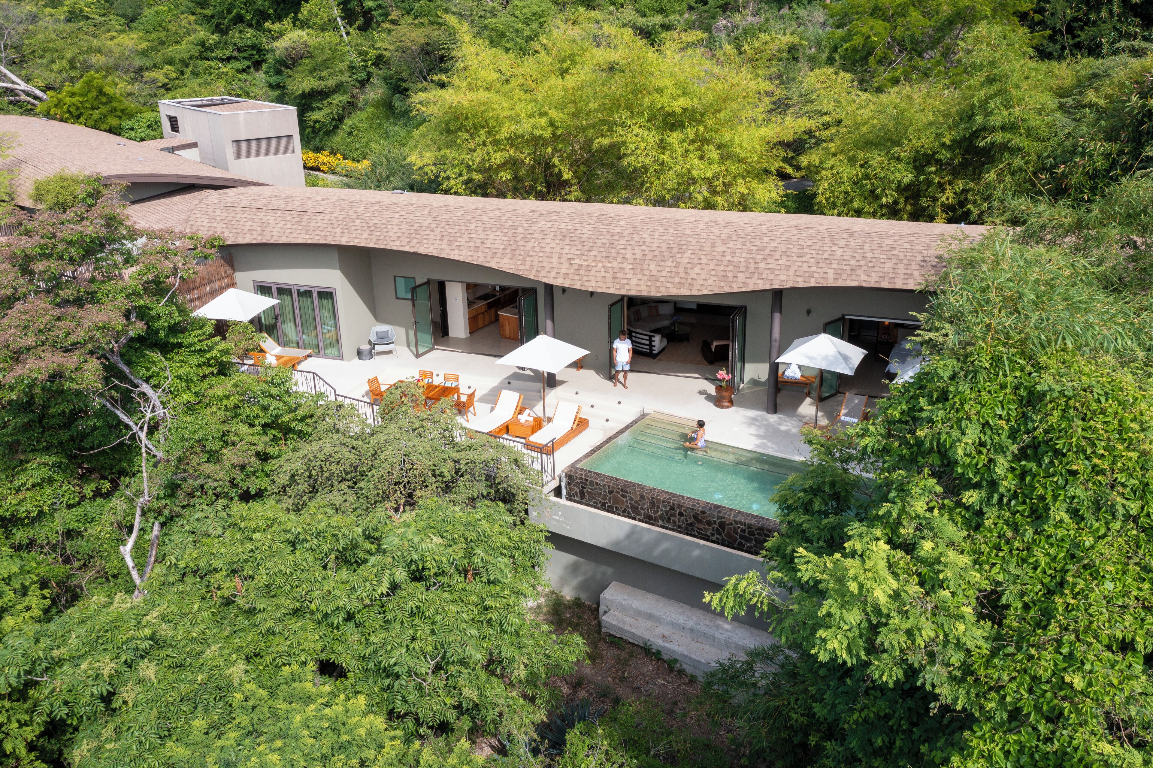 Una casa moderna con piscina, zona de estar exterior y un jardín grande.