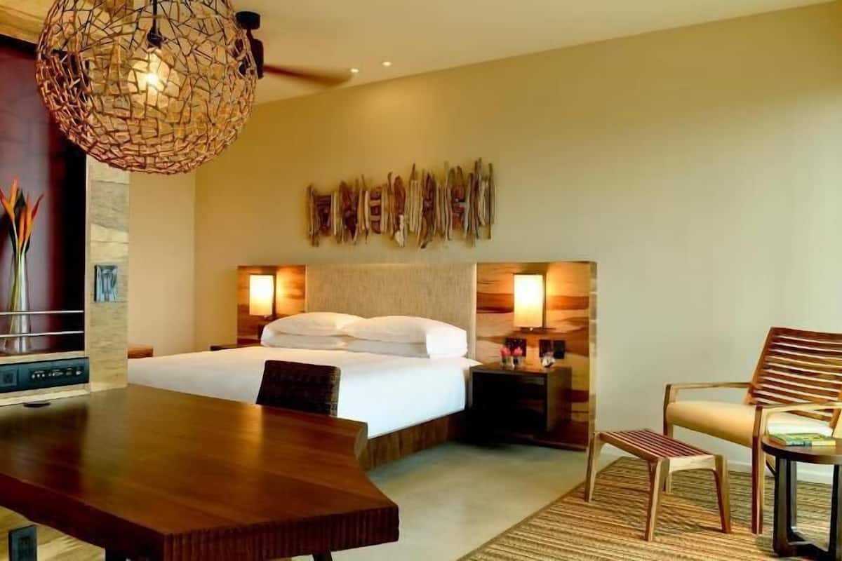 Ein Hotelzimmer mit Bett, Nachttischen, Schreibtisch, Stuhl und einem dekorativen Wandbild.