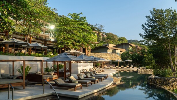 Een resort met een zwembad, ligbedden, parasols en een stenen muur.