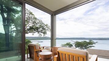 A modern room with large windows, wooden furniture, and a view of a lake and hills.