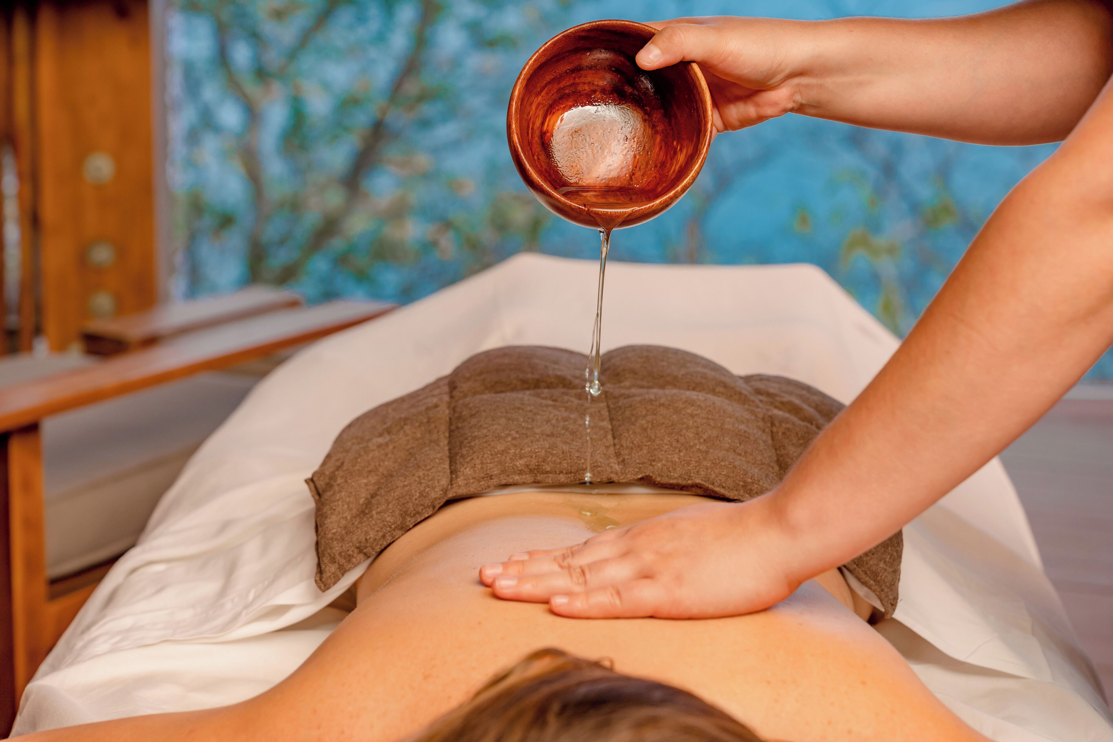 A person receiving a back massage with a towel draped over their head.