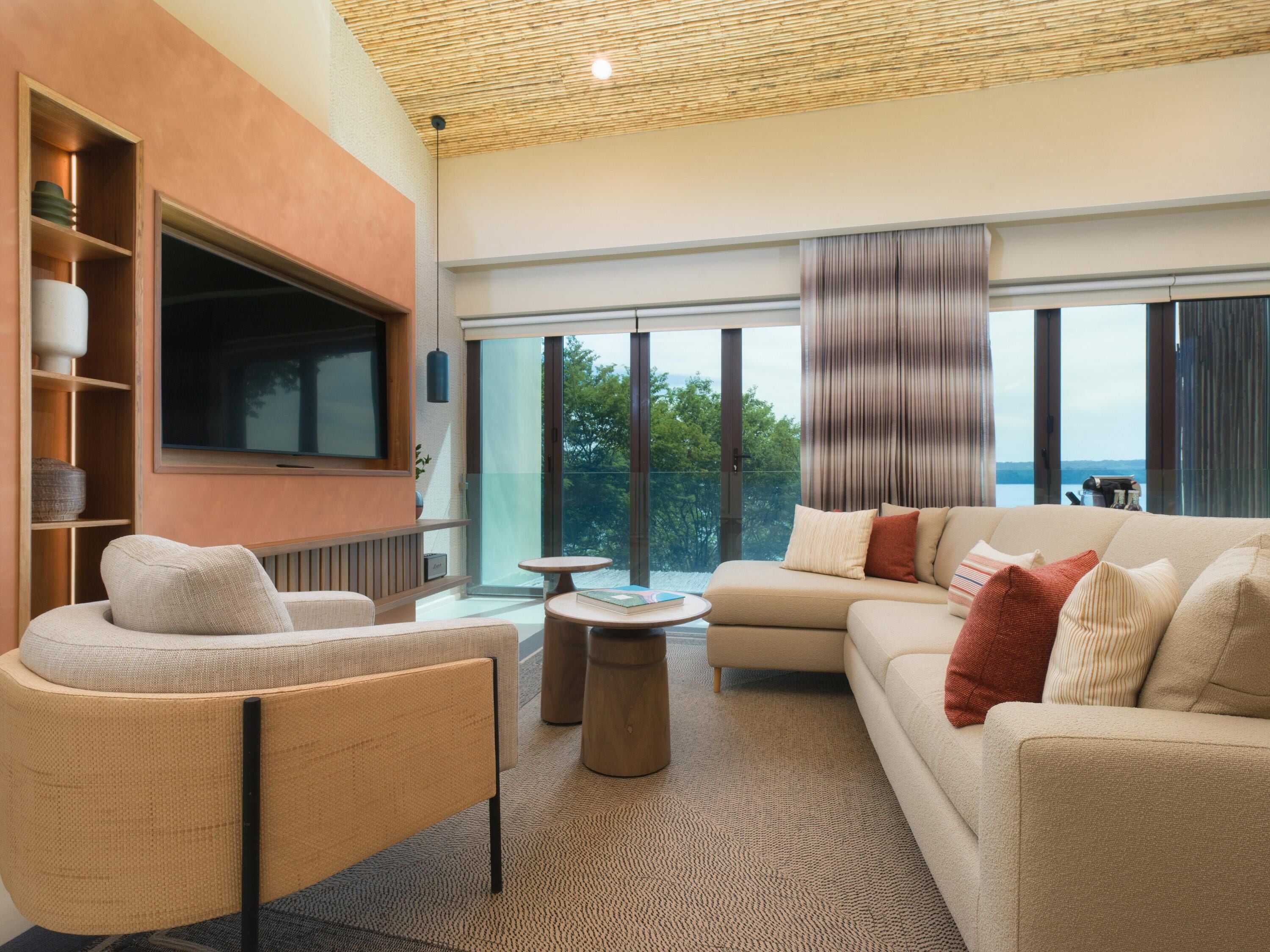 A modern living room with a sofa, armchair, and a flat-screen TV mounted on the wall.