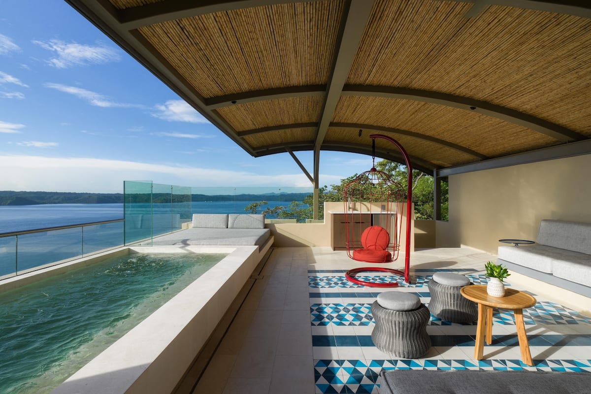 Ein moderner Außenbereich mit Lounge-Möbeln, Pool und Meerblick.