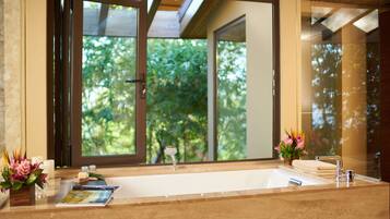 A bathroom with a large window, a bathtub, a sink, and a mirror.