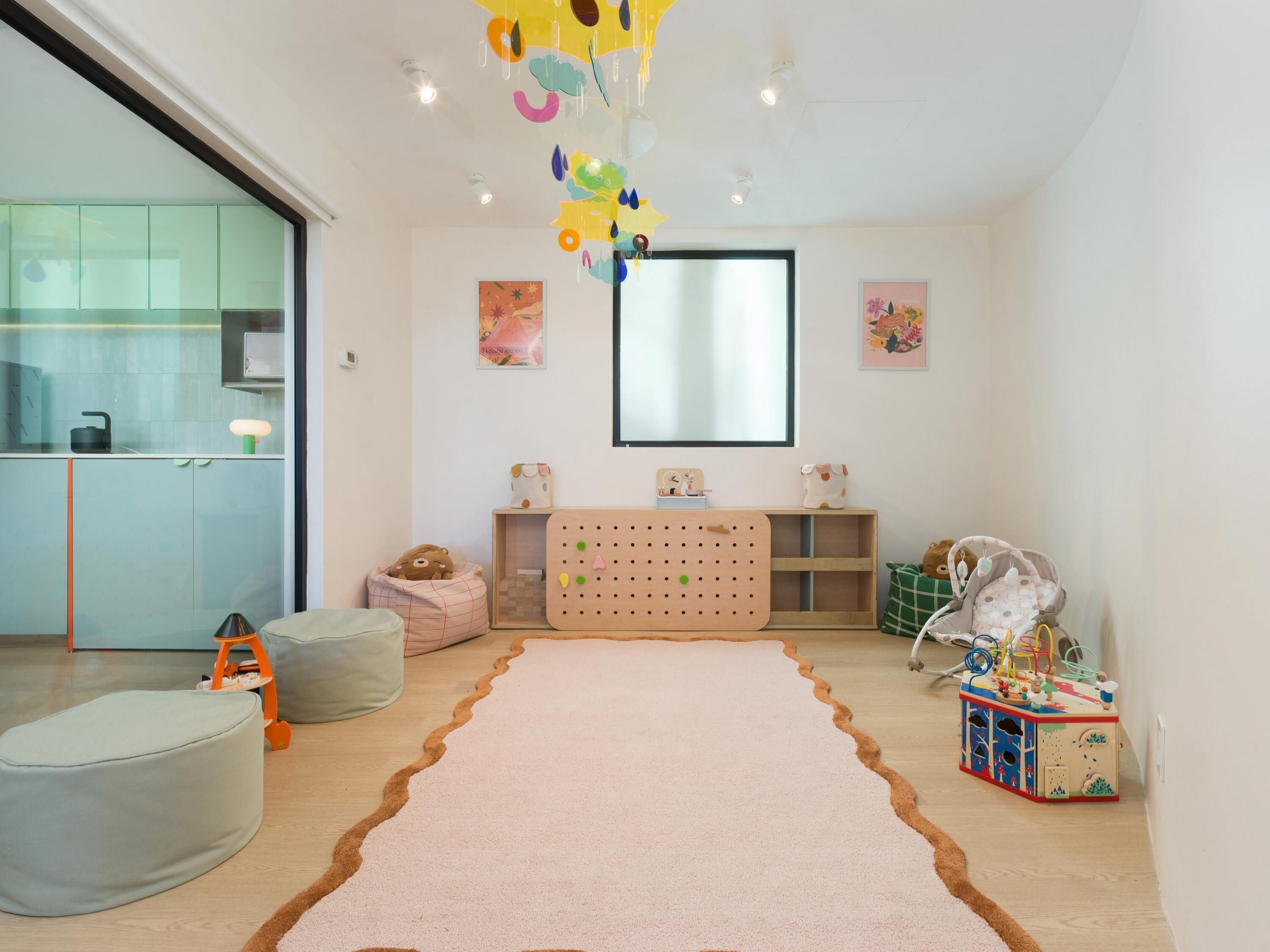 Ein Kinderzimmer mit großem Teppich, Sitzsäcken, einer Lochwand und einer Modelleisenbahn.