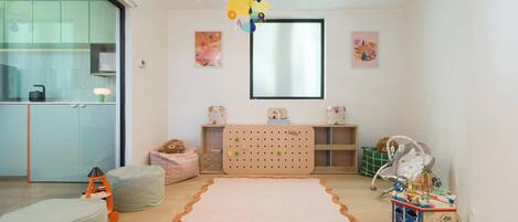 Ein Kinderzimmer mit großem Teppich, Sitzsäcken, einer Lochwand und einer Modelleisenbahn.