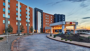 Um hotel moderno com uma entrada de cassino em destaque, vários andares e uma área de acesso ajardinada.