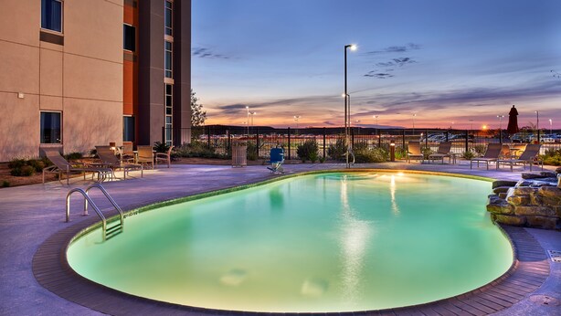 Piscina com espreguiçadeiras e vista para o horizonte urbano ao anoitecer.