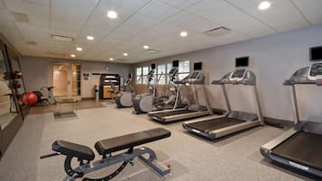A gym with treadmills, elliptical machines, and a bench.