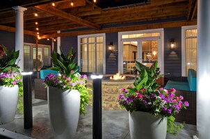An outdoor patio area with large planters of flowers, a fire pit, and a covered seating area.