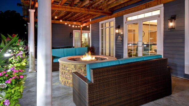 Un patio al aire libre con una chimenea, mobiliario de mimbre y una estructura de pérgola.