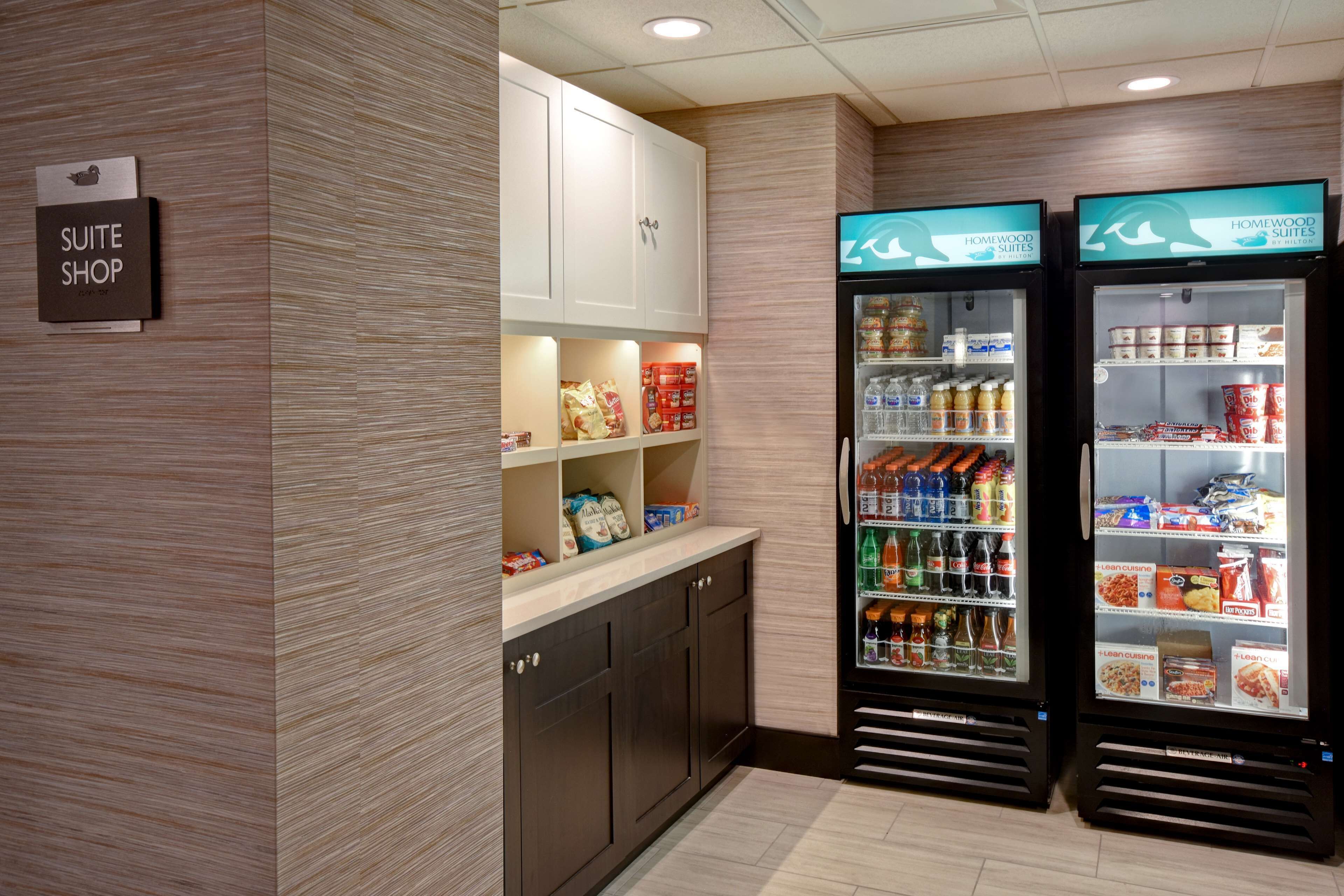 Tienda de suites de hotel con un letrero, kitchenette y dos dispensadores de bebidas.