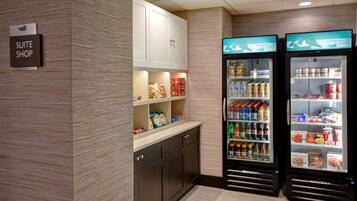 Tienda de suites de hotel con un letrero, kitchenette y dos dispensadores de bebidas.