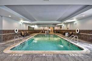 A large indoor swimming pool with a 'No Diving' sign, surrounded by lounge chairs and a tiled floor.
