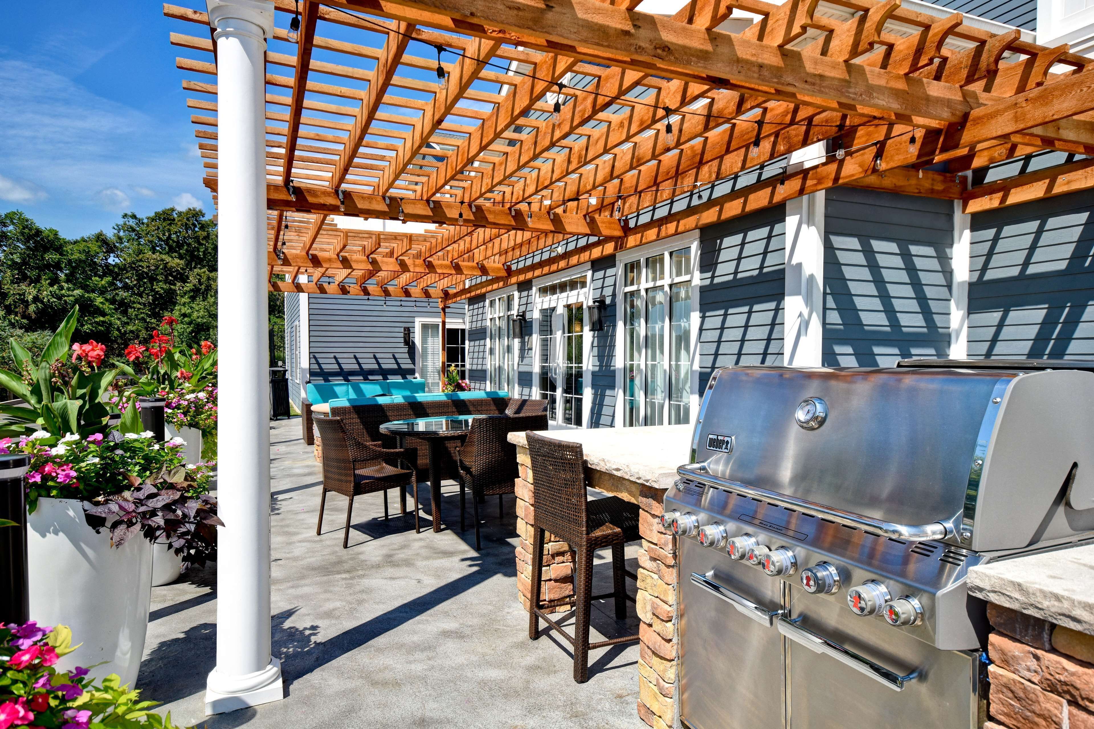 Une terrasse extérieure équipée d’un barbecue, de chaises en osier, d’une table de billard et d’une pergola.
